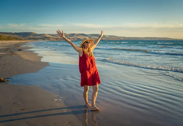 快乐迷人的成熟女人穿着红色的衣服 在户外享受着自由的海滩 张开双臂满怀希望地在放宽了验尸检疫之后 回到生活 户外和新的正常概念 — 图库照片