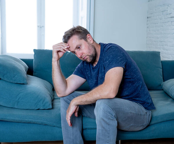 Unhappy depressed caucasian male crying in living room couch feeling desperate and lonely isolated at home. In stressed from work, unemployment, anxiety, heartbroken and depression concept