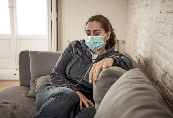 自宅のリビングルームのソファで保護顔マスクを持つ悲しいラテン語の女性は コロナウイルスのロックダウンや社会的距離の中で疲れや不安の苦しみうつ病を感じています 精神衛生と隔離の概念 — ストック写真