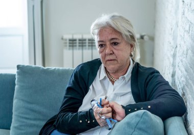 Yalnız, yaşlı, bunalımlı, dul bir kadın evde karantinada, üzgün ve endişeli bir şekilde ağlıyor. Kocası ve ailesi kayıp, COVID-19 salgını, tecrit, sosyal mesafeler ve zihinsel sağlık sorunları yaşıyor..