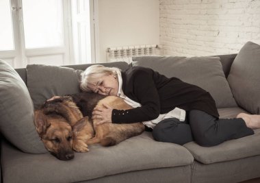 Bunalımlı yaşlı kadın evcil bir köpekle kanepede ağlıyordu. COVID-19 salgınının ortasında üzgün ve yorgun bir dul. Coronavirus ölümü, tecrit, sosyal uzaklık ve zihinsel sağlık.