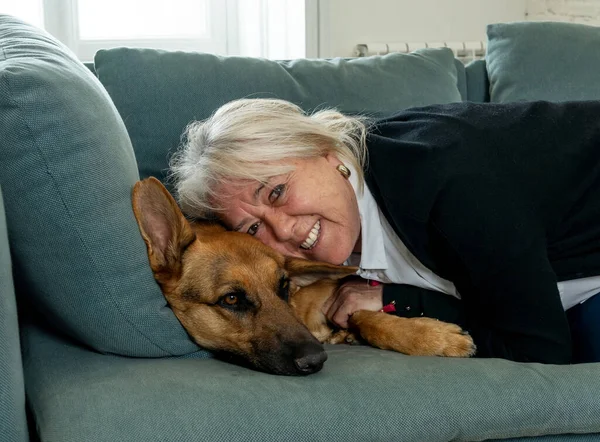 Confident senior woman loving and cuddling her cute pet big dog german shepherd enjoying life at home together. Positive image of life at home In Stay Home and animal benefits for mental health.