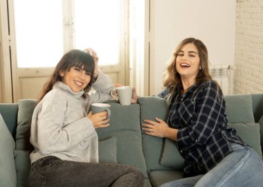 COVID-19 tecrit. Kendinden emin ve iyimser kadın sevgililer birlikte konuşuyor ve sıcak bir şeyler içiyor izole halde evde birlikte kalıyorlar. Evde kalın Sağlığınıza ve güvenliğinize dikkat edin.
