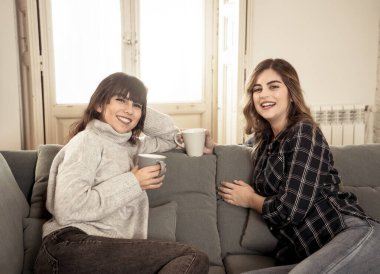 COVID-19 tecrit. Kendinden emin ve iyimser kadın sevgililer birlikte konuşuyor ve sıcak bir şeyler içiyor izole halde evde birlikte kalıyorlar. Evde kalın Sağlığınıza ve güvenliğinize dikkat edin.