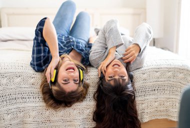 COVID-19 tecrit. Kendinden emin ve iyimser kadınlar en iyi kız arkadaşlar gülerek çevrimiçi müzik dinliyorlar evde yalnızken yatakta şarkı söyleyip dans ediyorlar. Evde güvenli sağlık ve güvenlik kampanyası yapın..