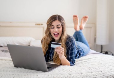 COVID-19 Salgını. Kapatma ve online alışveriş. Kredi kartıyla çekici genç bir kadın dizüstü bilgisayar kullanarak Coronavirus kilitleme ve sosyal uzaklık süresince evdeki internetten yemek alıyor..