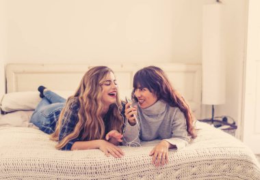 COVID-19 tecrit. Coronavirus sosyal mesafesi ve karantinası sırasında cep telefonuyla online müzik dinleyen kendinden emin ve pozitif kadın sevgililerin portresi. Evde kal, sağlıklı kal..
