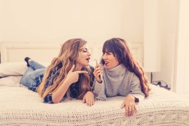 COVID-19 tecrit. Coronavirus sosyal mesafesi ve karantinası sırasında cep telefonuyla online müzik dinleyen kendinden emin ve pozitif kadın sevgililerin portresi. Evde kal, sağlıklı kal..