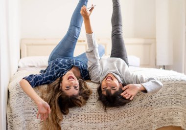 COVID-19 tecrit. Coronavirus sosyal mesafesi ve karantinası sırasında cep telefonuyla online müzik dinleyen kendinden emin ve pozitif kadın sevgililerin portresi. Evde kal, sağlıklı kal..