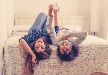 COVID-19 tecrit. Coronavirus sosyal mesafesi ve karantinası sırasında cep telefonuyla online müzik dinleyen kendinden emin ve pozitif kadın sevgililerin portresi. Evde kal, sağlıklı kal..
