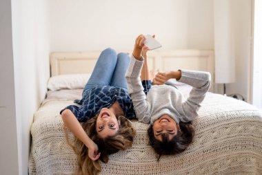 COVID-19 tecrit. Coronavirus sosyal mesafesi ve karantinası sırasında cep telefonuyla online müzik dinleyen kendinden emin ve pozitif kadın sevgililerin portresi. Evde kal, sağlıklı kal..