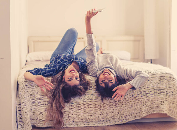 COVID-19 Lockdown. Portrait of confident and positive women girlfriends listening online music together on mobile phone during coronavirus social distancing and quarantine. Stay home stay healthy.