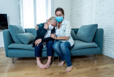Depresyondaki anne ve kızı tıbbi maske takıp ağlıyorlar ve Coronavirus 'la savaşan sevdiklerinin yasını tutuyorlar. COVID-19 salgınından etkilenen insanlar ve aileler.