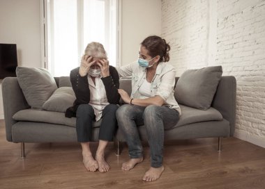 Depresyondaki anne ve kızı tıbbi maske takıp ağlıyorlar ve Coronavirus 'la savaşan sevdiklerinin yasını tutuyorlar. COVID-19 salgınından etkilenen insanlar ve aileler.