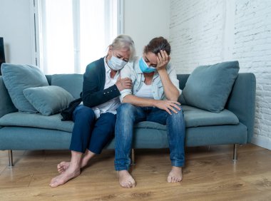 Depresyondaki anne ve kızı tıbbi maske takıp ağlıyorlar ve Coronavirus 'la savaşan sevdiklerinin yasını tutuyorlar. COVID-19 salgınından etkilenen insanlar ve aileler.