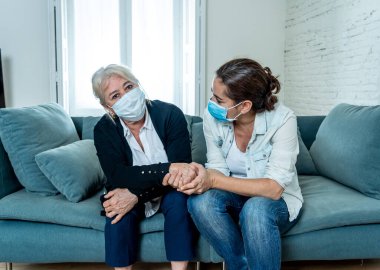 Depresyondaki anne ve kızı tıbbi maske takıp ağlıyorlar ve Coronavirus 'la savaşan sevdiklerinin yasını tutuyorlar. COVID-19 salgınından etkilenen insanlar ve aileler.