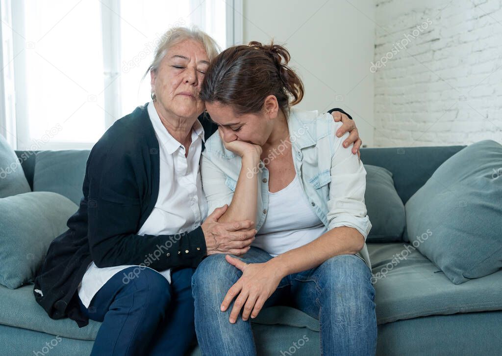 Senior mother comforting adult daughter grieving loss of loved one fighting the Coronavirus. Elderly mother embracing adult daughter suffering from depression. People affected by COVID-19 outbreak.