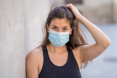Halka açık yerlerde cerrahi maske takan genç bir kadın. Coronavirus grip virüslerine ve hastalıklara karşı koruyucu maske yayıyor. COVID-19 'dan sonraki Yeni Normal yaşamın olumlu görüntüsü