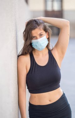 Halka açık yerlerde cerrahi maske takan genç bir kadın. Coronavirus grip virüslerine ve hastalıklara karşı koruyucu maske yayıyor. COVID-19 'dan sonraki Yeni Normal yaşamın olumlu görüntüsü