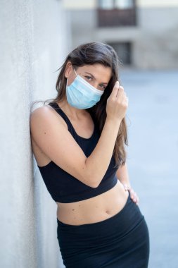 Halka açık yerlerde cerrahi maske takan genç bir kadın. Coronavirus grip virüslerine ve hastalıklara karşı koruyucu maske yayıyor. COVID-19 'dan sonraki Yeni Normal yaşamın olumlu görüntüsü