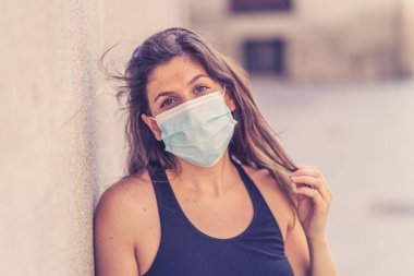 Halka açık yerlerde cerrahi maske takan genç bir kadın. Coronavirus grip virüslerine ve hastalıklara karşı koruyucu maske yayıyor. COVID-19 'dan sonraki Yeni Normal yaşamın olumlu görüntüsü
