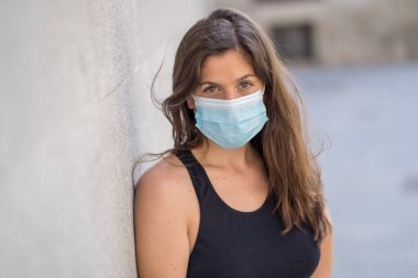 Halka açık yerlerde cerrahi maske takan genç bir kadın. Coronavirus grip virüslerine ve hastalıklara karşı koruyucu maske yayıyor. COVID-19 'dan sonraki Yeni Normal yaşamın olumlu görüntüsü