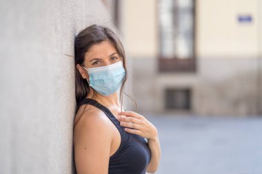 Halka açık yerlerde cerrahi maske takan genç bir kadın. Coronavirus grip virüslerine ve hastalıklara karşı koruyucu maske yayıyor. COVID-19 'dan sonraki Yeni Normal yaşamın olumlu görüntüsü