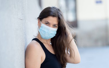 Halka açık yerlerde cerrahi maske takan genç bir kadın. Coronavirus grip virüslerine ve hastalıklara karşı koruyucu maske yayıyor. COVID-19 'dan sonraki Yeni Normal yaşamın olumlu görüntüsü