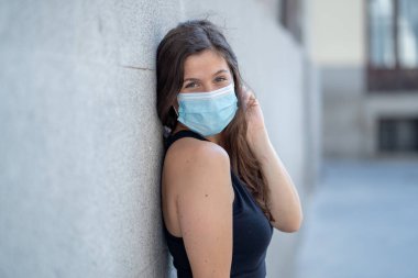 Halka açık yerlerde cerrahi maske takan genç bir kadın. Coronavirus grip virüslerine ve hastalıklara karşı koruyucu maske yayıyor. COVID-19 'dan sonraki Yeni Normal yaşamın olumlu görüntüsü