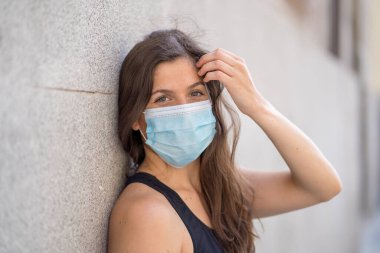 Halka açık yerlerde cerrahi maske takan genç bir kadın. Coronavirus grip virüslerine ve hastalıklara karşı koruyucu maske yayıyor. COVID-19 'dan sonraki Yeni Normal yaşamın olumlu görüntüsü