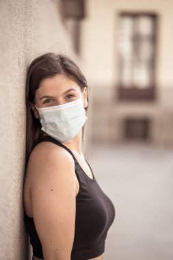Halka açık yerlerde cerrahi maske takan genç bir kadın. Coronavirus grip virüslerine ve hastalıklara karşı koruyucu maske yayıyor. COVID-19 'dan sonraki Yeni Normal yaşamın olumlu görüntüsü