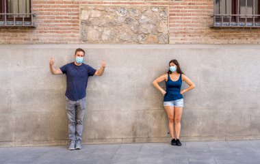 Korumacı yüz maskeleri takan erkek ve kadın birbirlerinden 2 metre uzakta duruyorlar. Sosyal mesafeyi koronavirüsün yayılmasını önlüyorlar. COVID-19 hastalıkların korunmasının kavramsal görüntüsü ve Yeni Normal.