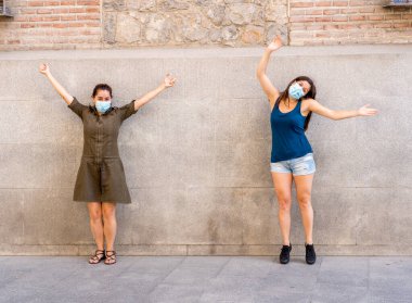 Korumacı yüz maskeleri takan erkek ve kadın birbirlerinden 2 metre uzakta duruyorlar. Sosyal mesafeyi koronavirüsün yayılmasını önlüyorlar. COVID-19 hastalıkların korunmasının kavramsal görüntüsü ve Yeni Normal.