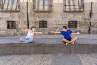 Korumacı yüz maskeleri takan erkek ve kadın birbirlerinden 2 metre uzakta duruyorlar. Sosyal mesafeyi koronavirüsün yayılmasını önlüyorlar. COVID-19 hastalıkların korunmasının kavramsal görüntüsü ve Yeni Normal.