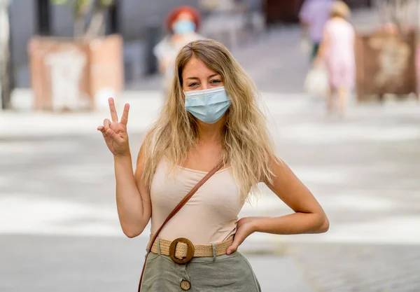 Young woman wearing protective face mask outdoors in city street. Positive image of New Normal life after COVID-19 and health protocols to avoid infections and the virus spread in public spaces.