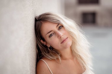 Açık havada, güzel sarı saçları ve şehvetli gülüşü olan çekici genç bir kadının portresi var. Doğal güzellik ve ışıkla poz veren kadın model. Gerçek insanlar, güzellik, moda ve yaşam tarzı.