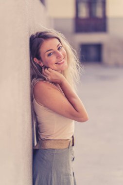 Açık havada, güzel sarı saçları ve şehvetli gülüşü olan çekici genç bir kadının portresi var. Doğal güzellik ve ışıkla poz veren kadın model. Gerçek insanlar, güzellik, moda ve yaşam tarzı.