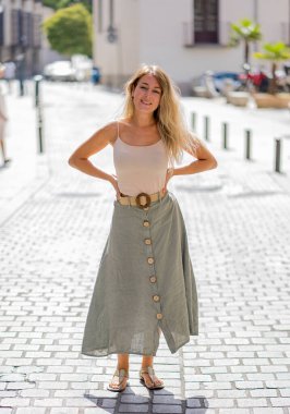 Açık havada, güzel sarı saçları ve şehvetli gülüşü olan çekici bir kadının uzun boylu portresi. Doğal güzellik ve ışıkla poz veren kadın model. Gerçek insanlar, güzellik, moda ve yaşam tarzı.