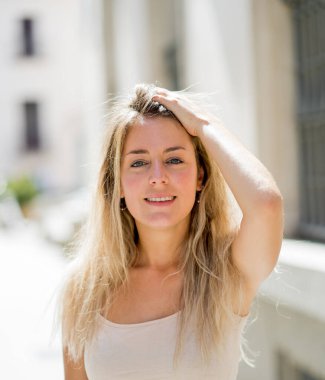 Açık havada, güzel sarı saçları ve şehvetli gülüşü olan çekici genç bir kadının portresi var. Doğal güzellik ve ışıkla poz veren kadın model. Gerçek insanlar, güzellik, moda ve yaşam tarzı.