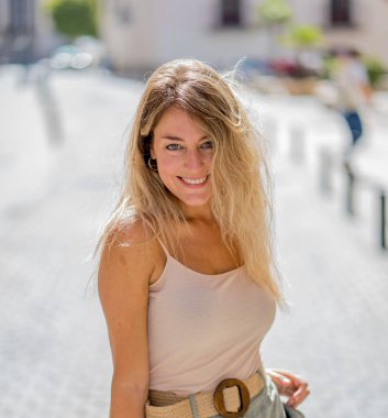 Açık havada, güzel sarı saçları ve şehvetli gülüşü olan çekici genç bir kadının portresi var. Doğal güzellik ve ışıkla poz veren kadın model. Gerçek insanlar, güzellik, moda ve yaşam tarzı.