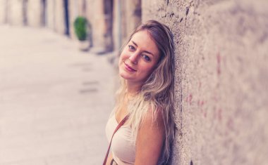 Açık havada, güzel sarı saçları ve şehvetli gülüşü olan çekici genç bir kadının portresi var. Doğal güzellik ve ışıkla poz veren kadın model. Gerçek insanlar, güzellik, moda ve yaşam tarzı.