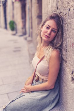 Açık havada, güzel sarı saçları ve şehvetli gülüşü olan çekici genç bir kadının portresi var. Doğal güzellik ve ışıkla poz veren kadın model. Gerçek insanlar, güzellik, moda ve yaşam tarzı.