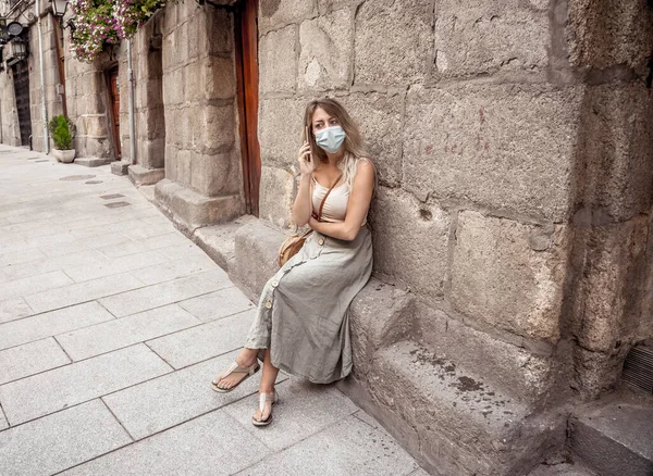 Ung Kvinna Stadens Gata Bär Skyddande Ansiktsmask Och Använder Mobiltelefon — Stockfoto
