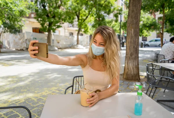 Ung Kvinna Med Skyddsmask Och Handdesinfektionsmedel Videosamtal Med Mobiltelefon Caféet — Stockfoto