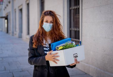 İş bölgesinde tıbbi koruyucu maskeli üzgün bir iş kadını bir kutu ofis çalışanı iş kaybından dolayı depresyonda. Coronavirus iş kesintileri, COVID-19 işsizlik ve ekonomik kriz kavramı.