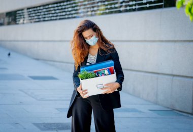 Ofis dışında yüz maskesi takan depresyondaki iş kadını işten kovulduktan sonra kendini umutsuz hissediyor. Coronavirus iş kayıpları, işten çıkarma ve COVID-19 salgını istihdam üzerinde etki.