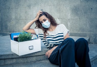 İş bölgesinde tıbbi koruyucu maskeli üzgün bir iş kadını bir kutu ofis çalışanı iş kaybından dolayı depresyonda. Coronavirus iş kesintileri, COVID-19 işsizlik ve ekonomik kriz kavramı.