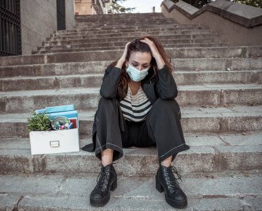 COVID-19 işten çıkarma ve işsizlik. Ofis dışında yüz maskesi takan depresyondaki iş kadını Coronavirus 'un iş kesintileri yüzünden işini kaybettikten sonra kendini umutsuz hissediyor..