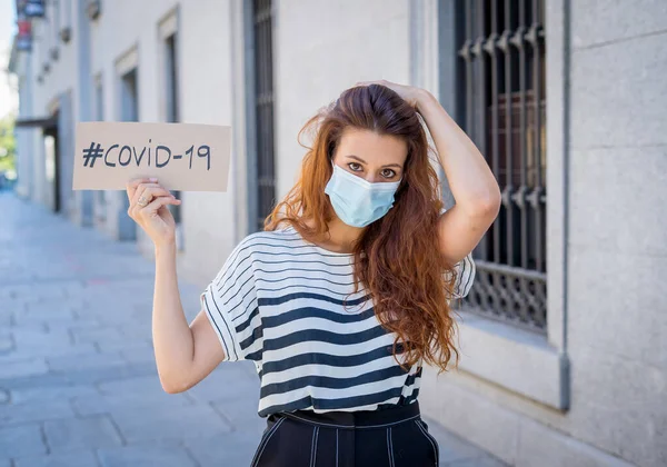 Portrait of sad depressed woman in medical protective face mask holding COVID-19 sign. Coronavirus Outbreak, unemployment, Health and global economic and financial crisis.