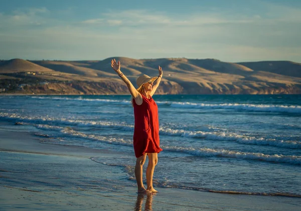 快乐迷人的成熟女人 穿着红色衣服 在户外尽情享受 在海滩上自由自在 张开双臂 伸展着蓝色的大海和美丽的风景 希望和福祉概念 — 图库照片